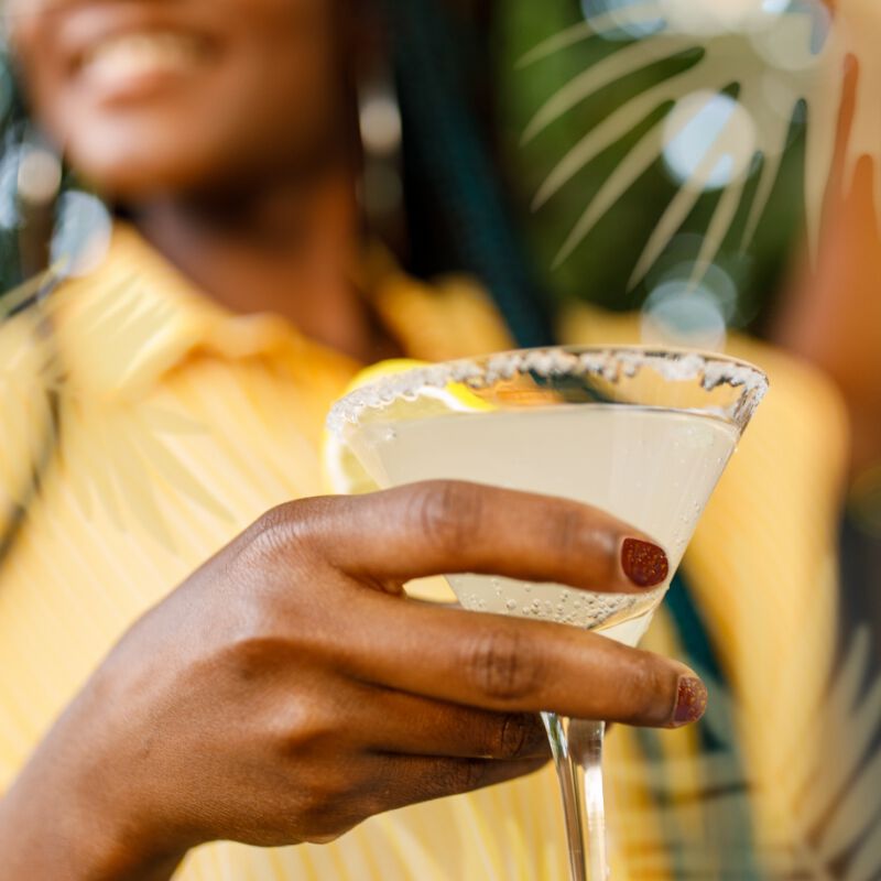 A woman holding a cocktail in the sun