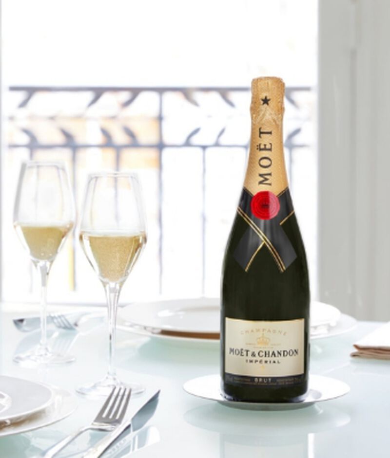 A bottle of Moët & Chandon Imperial Brut with two flute glasses on a table