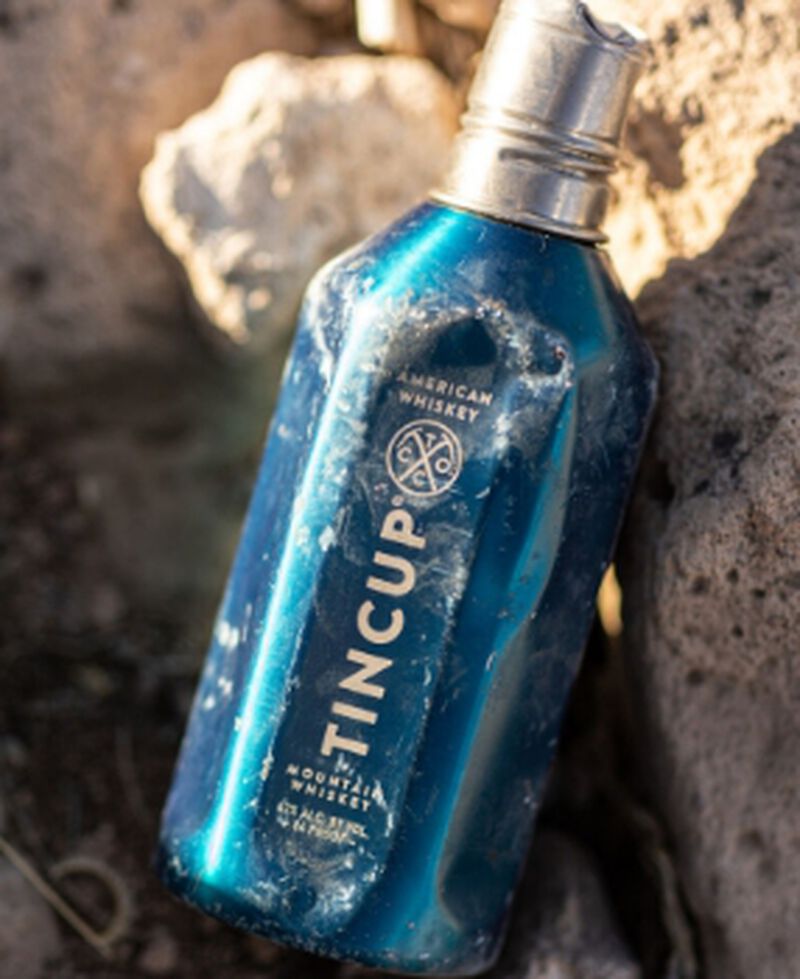 A reusable bottle of Tincup® Adventure Pack sitting on a rock